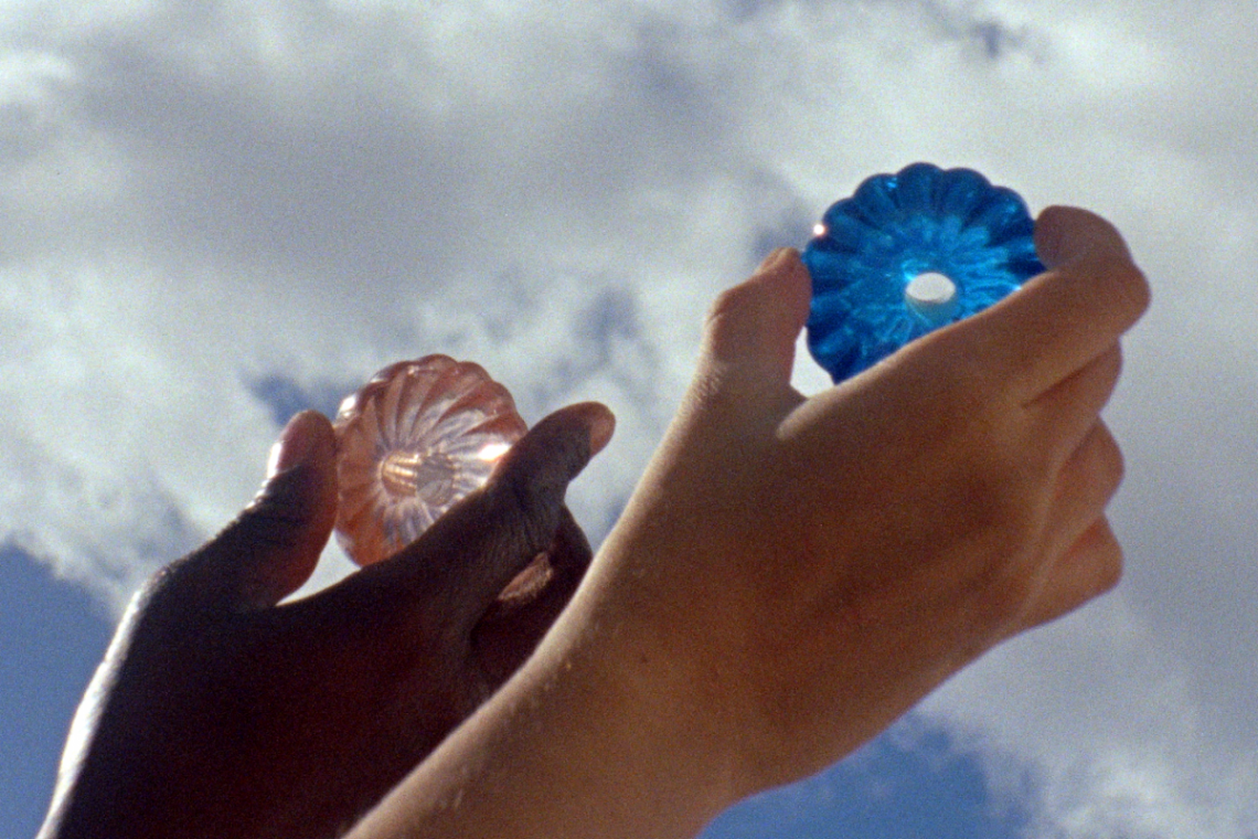 Two hands holding two objects, one blue and one pink