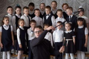 A teacher arranges a mic in front of a group of young children
